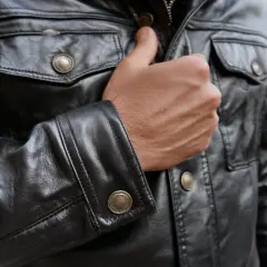 Mężczyzna w czarnej, skórzanej kurtce z ozdobnymi guzikami. Kto przerabia kurtki skórzane? Ten styl to klasyka.