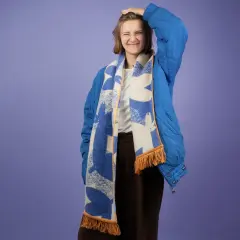 Dziewczyna w niebieskiej kurtce z kapturem i wzorzystym szaliku. Pokazuje, jak nosić szalik do kurtki z kapturem, tworząc stylowy look.