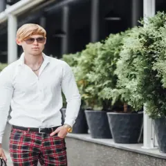 Elegancki mężczyzna w białej koszuli i spodniach w czerwoną kratę. Idealne połączenie, by zadać sobie pytanie: jaka koszula do spodni w kratę?