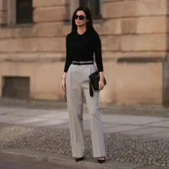 Eleganckie stylizacje na urodziny w domu: czarny sweterek, szerokie spodnie i kopertówka. Idealny zestaw na domowe przyjęcie.