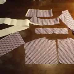 Kawałki materiału w paski, gotowe do szycia. Zastanawiasz się, jak poszerzyć bluzkę koszulową? Te elementy to pierwszy krok do stworzenia nowej kreacji.