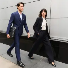 Para idąca ulicą w eleganckich, granatowych garniturach, przykład biznesowego stylu formalnego.