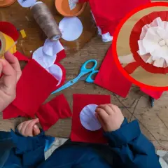 Dzieci tworzą kotyliony z czerwonego i białego materiału, przygotowując się do nauki, jak przypiąć kotylion do bluzki.