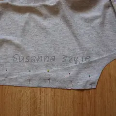 Szara tkanina bluzki z naszytymi szpilkami, gotowa do zwężenia pod pachami.