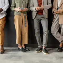Cztery osoby w eleganckich strojach, trzymające telefony. Wszyscy przestrzegają dress code elegant.