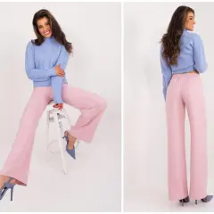 Modelka w swetrze i szerokich spodniach w kolorze pudrowy róż. Elegancki zestaw na co dzień.