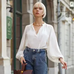 Elegancka biała bluzka z bufiastymi rękawami i jeansowe, szerokie spodnie. Idealna stylizacja, która odpowiada na pytanie: jaka bluzka do szerokich spodni.