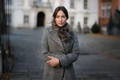 Elegancka kobieta w szarym płaszczu z futrzanym kołnierzem, idealnym okryciu wierzchnim na chłodne dni.