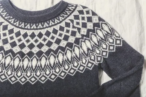 Sfilcowany sweter z granatowej wełny z białym, geometrycznym wzorem. Idealny na chłodne dni.