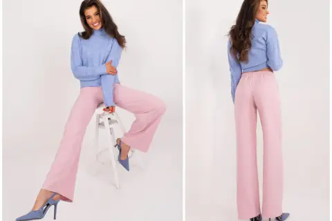 Modelka w swetrze i szerokich spodniach w kolorze pudrowy róż. Elegancki zestaw na co dzień.