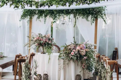 Udekorowany bukietami kwiatów stół i krzesła tworzą romantyczną stylizację boho na wesele.