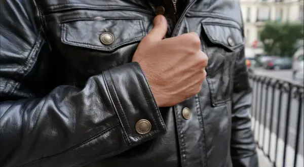 Mężczyzna w czarnej, skórzanej kurtce z ozdobnymi guzikami. Kto przerabia kurtki skórzane? Ten styl to klasyka.