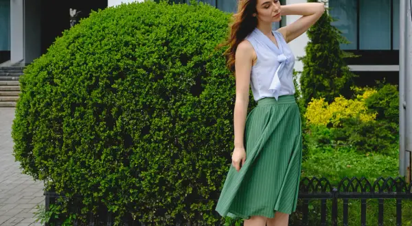 Elegancka stylizacja: błękitna bluzka z kokardą i zielona spódnica w paski. Idealna odpowiedź na pytanie: jaka bluzka do zielonej spódnicy.