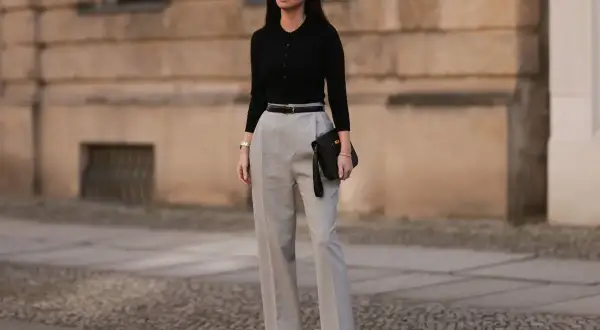 Eleganckie stylizacje na urodziny w domu: czarny sweterek, szerokie spodnie i kopertówka. Idealny zestaw na domowe przyjęcie.