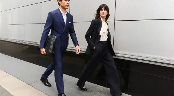 Para idąca ulicą w eleganckich, granatowych garniturach, przykład biznesowego stylu formalnego.