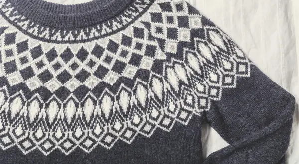 Sfilcowany sweter z granatowej wełny z białym, geometrycznym wzorem. Idealny na chłodne dni.