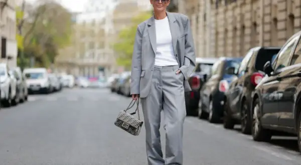 Elegancki damski garnitur w stylu smart casual, biały top, sneakersy i torebka Fendi.