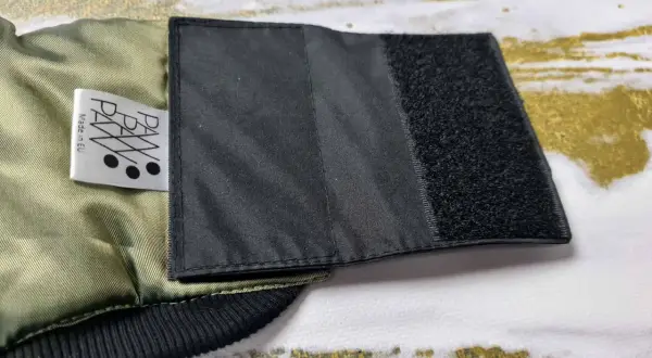 Fragment kurtki z naszytym rzepem, pokazujący, jak poszerzyć kurtkę. Metka "PAW Made in EU".