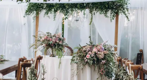 Udekorowany bukietami kwiatów stół i krzesła tworzą romantyczną stylizację boho na wesele.