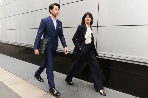 Para idąca ulicą w eleganckich, granatowych garniturach, przykład biznesowego stylu formalnego.