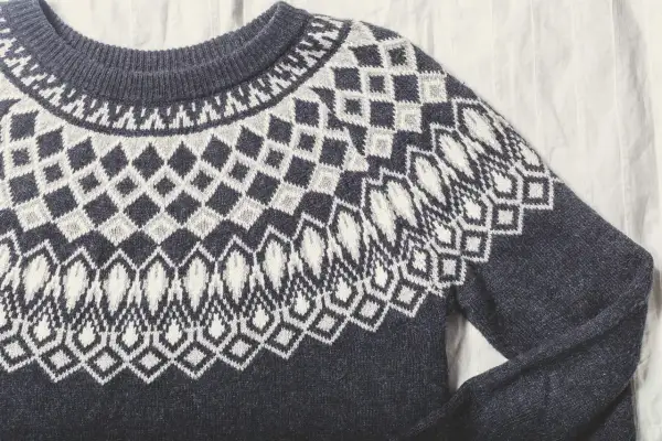Sfilcowany sweter z granatowej wełny z białym, geometrycznym wzorem. Idealny na chłodne dni.