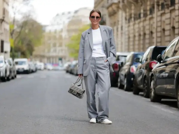 Elegancki damski garnitur w stylu smart casual, biały top, sneakersy i torebka Fendi.
