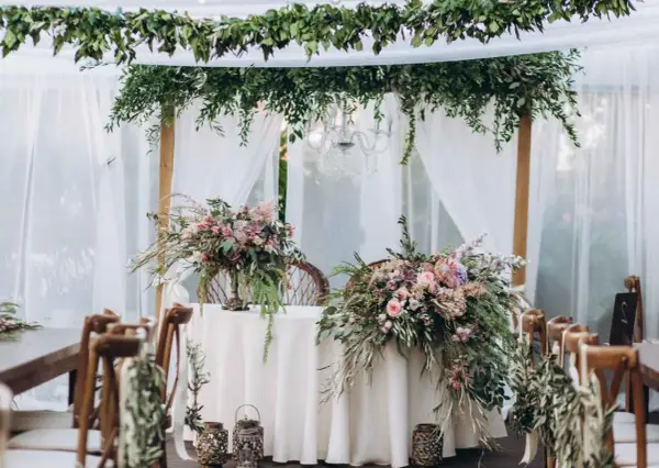 Udekorowany bukietami kwiatów stół i krzesła tworzą romantyczną stylizację boho na wesele.